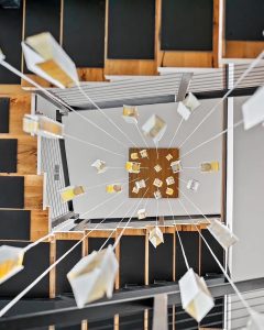 White SunBeam chandelier installation above spiral staircase