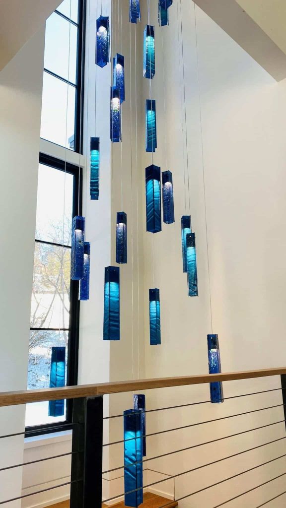 Blue SunBeam chandelier installation above spiral staircase