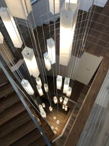 Cascading Murano glass chandelier installation in high-ceiling foyer